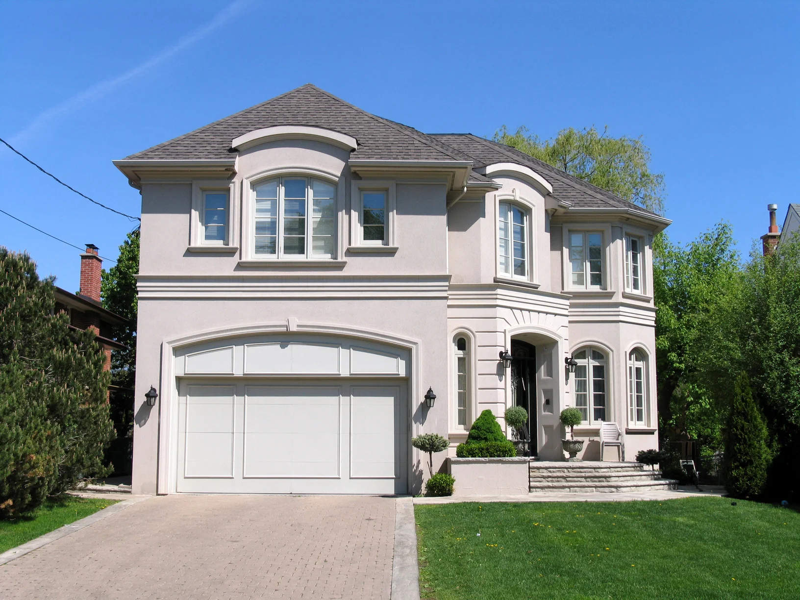Creamy stucco house with dark grey roofing