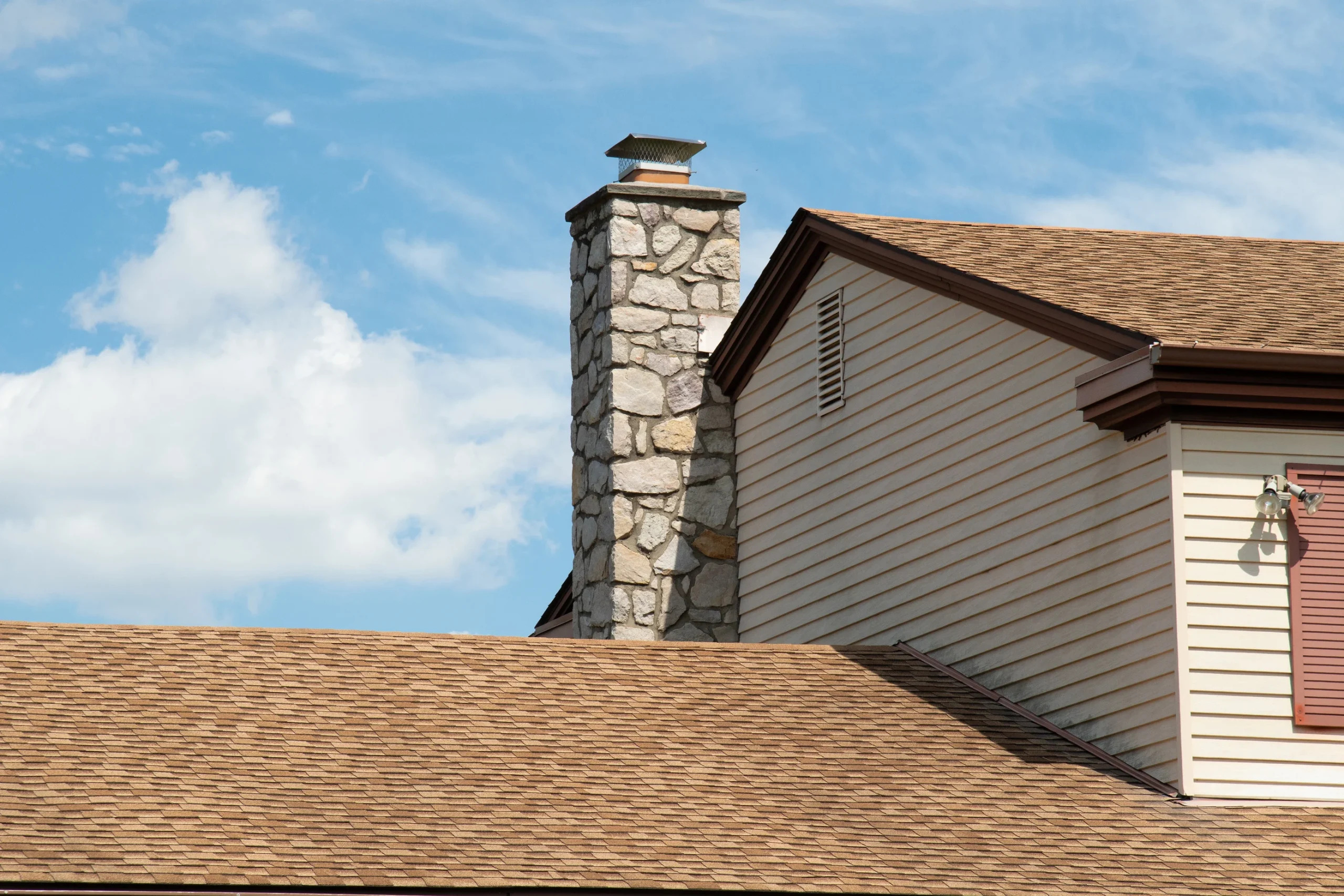 House with creamy horizontal siding and bricked chimney